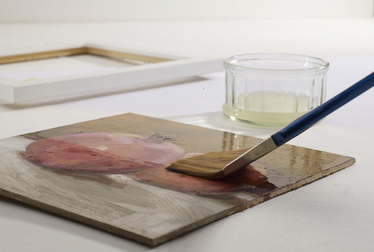 applying varnish to a painting with a wide brush